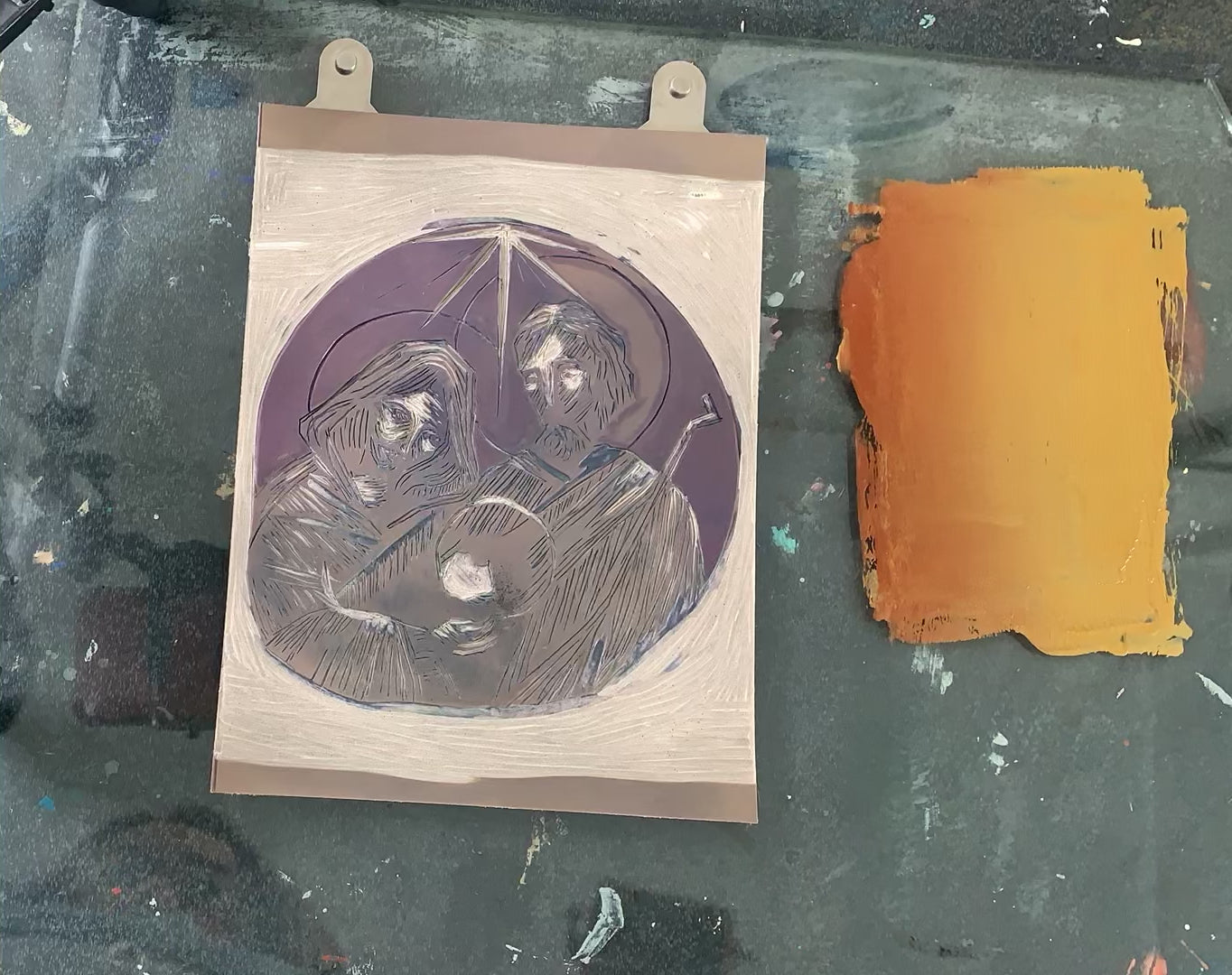Proceso de entintado con rodillo de la placa de linóleo numero 1.   Se puede apreciar que son 2 colores de tinta: café y oro metálico;  logrando un degradado en espejo, de forma que en el centro de la placa (bajo la estrella) quede un tono oro, simulando la luz de la estrella.