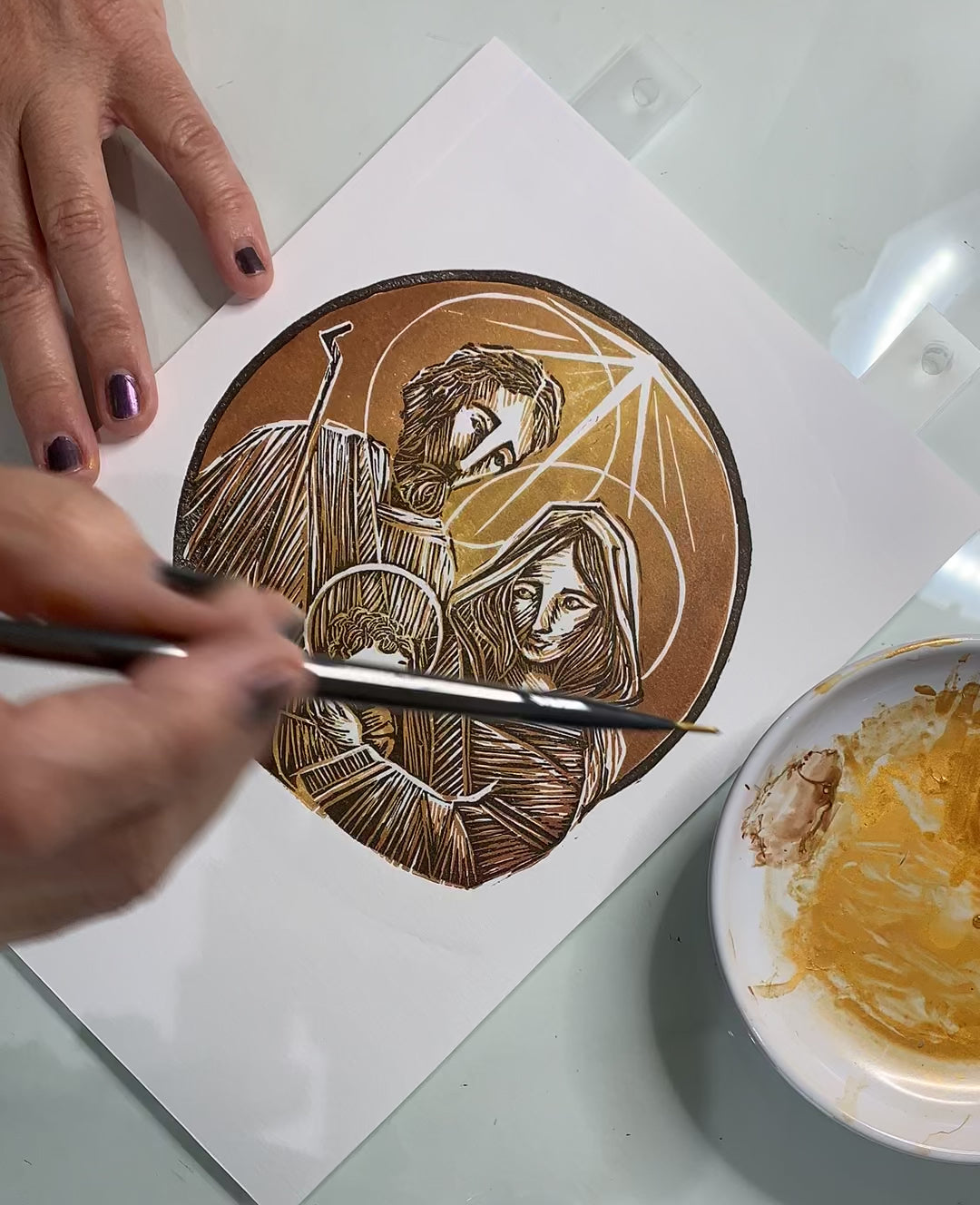 Proceso de aplicación de acuarela color oro metálico con pincel, en algunas áreas del grabado.